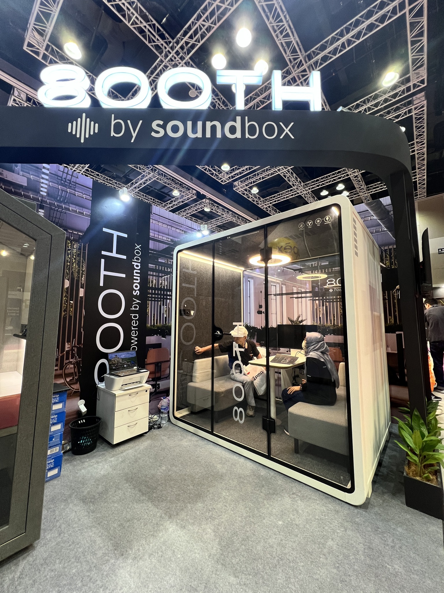 800TH by Soundbox exhibition entrance at Archidex, featuring a large acoustic booth with two people working inside at a built-in desk with monitors