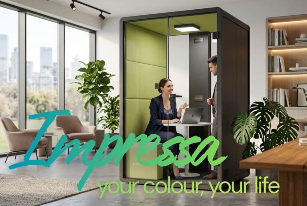 Woman working on a laptop inside a green-panelled 8OOTH Impressa booth while a colleague looks in, in a bright office