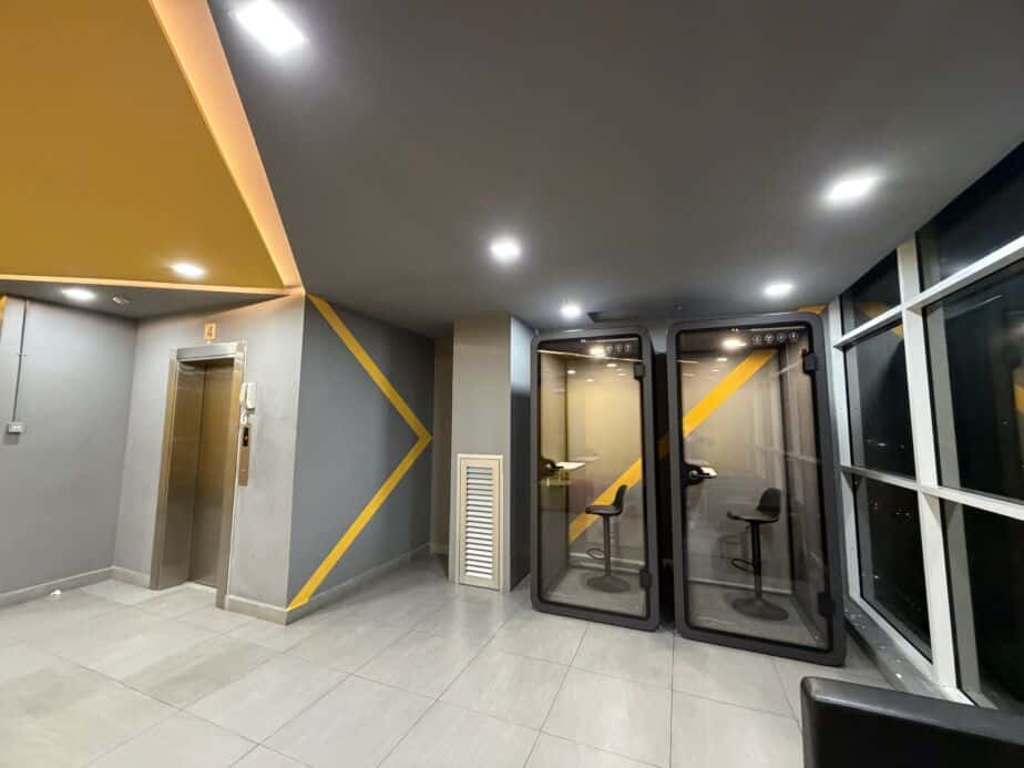 Two acoustic booths with bar stools near a lift lobby