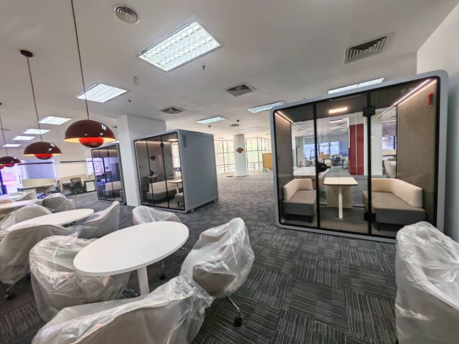 Acoustic booths in an office fit-out with furniture wrapped in protective plastic