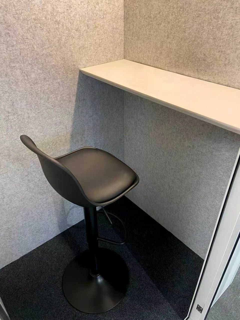 Interior of an 8OOTH Nexus booth showing the acoustic felt wall lining, built-in desk shelf and adjustable stool