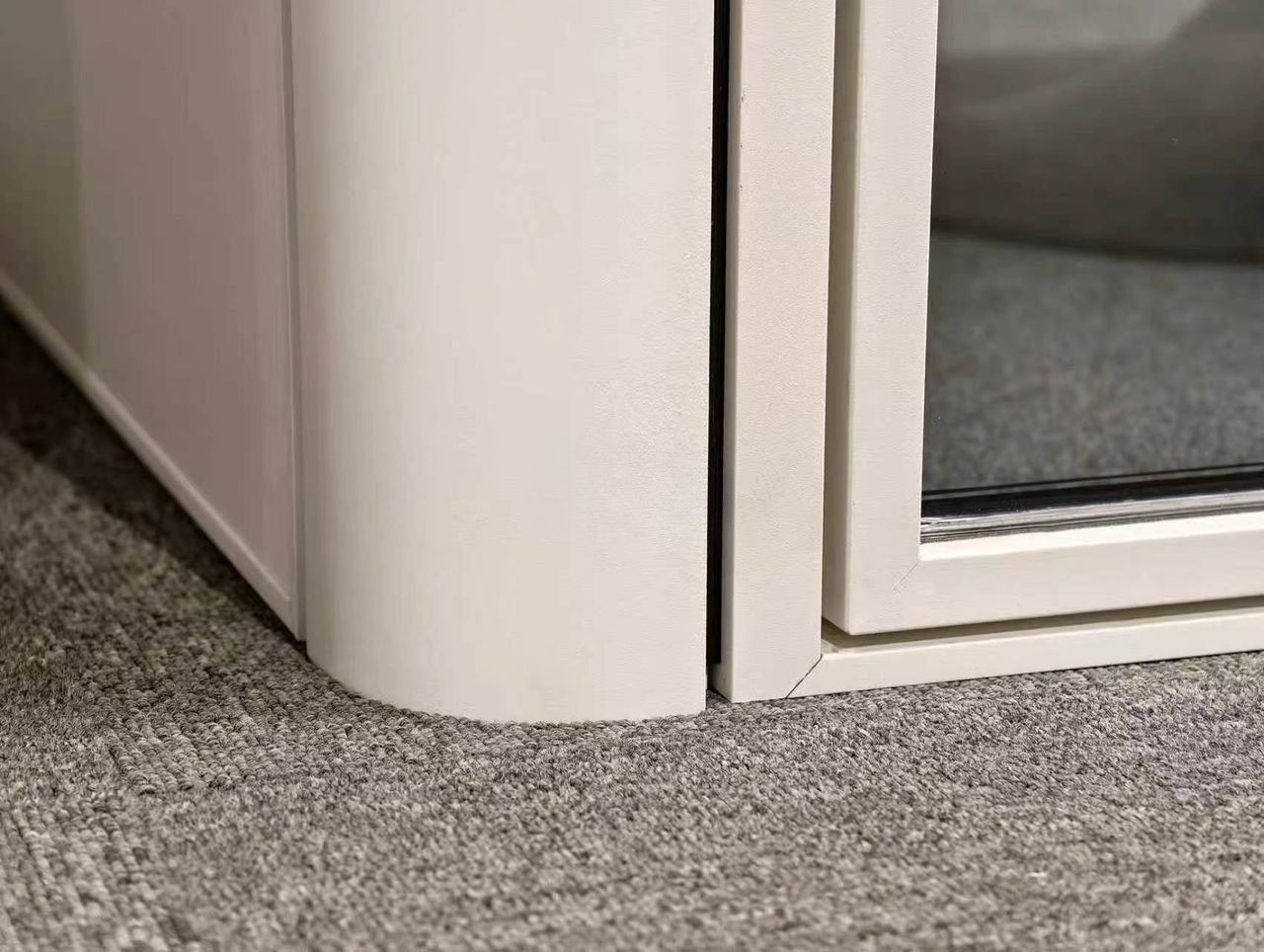 Close-up of an 8OOTH booth's rounded corner panel and glass door frame, showing build and finish quality